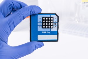 Scienziato con guanti blu in un laboratorio che tiene un chip di sequenziamento del DNA