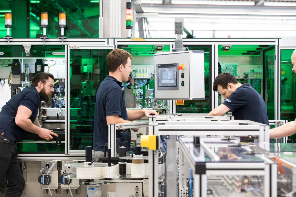 Three male employees build a machine for a pharmaceutical manufacturing customer