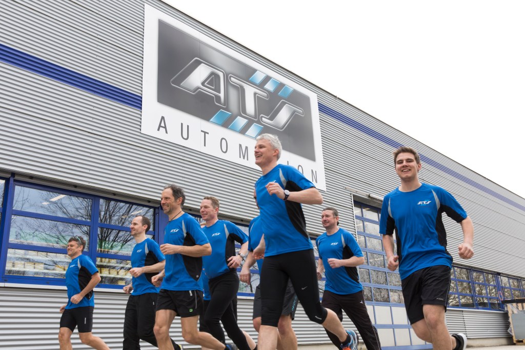 A group of employees run past an ATS Automation building as part of a charity event