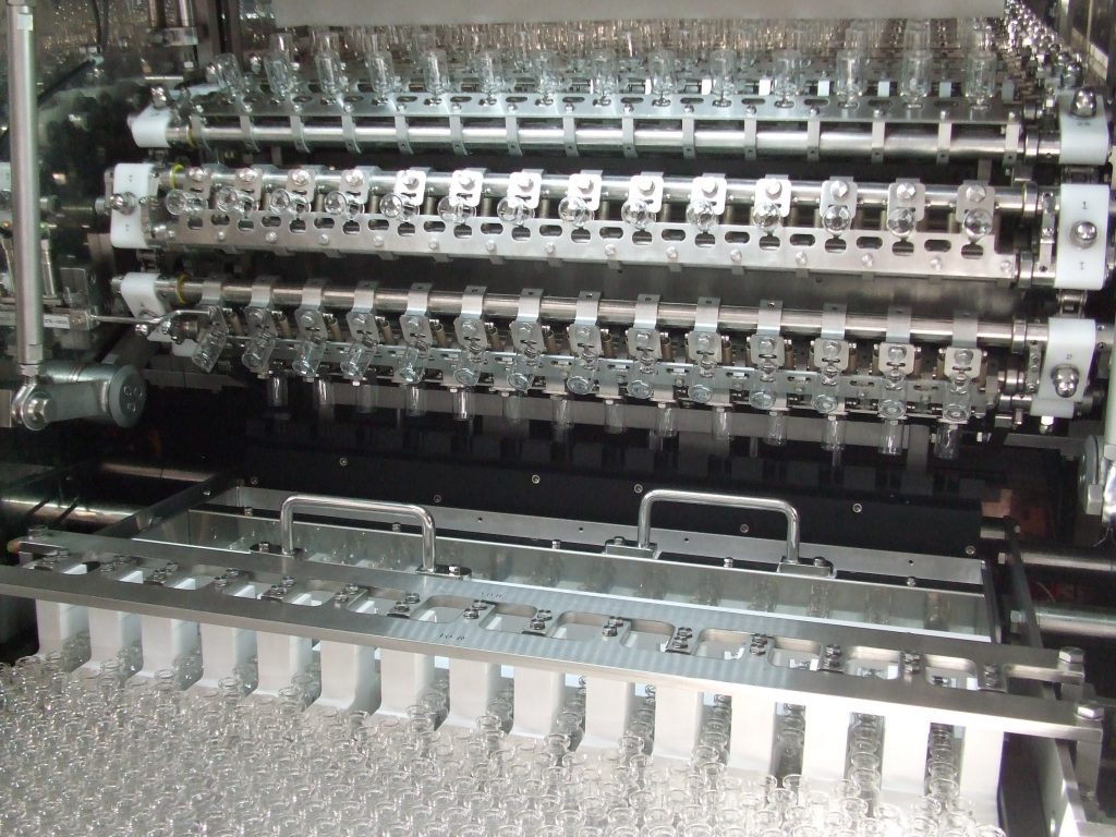 Part of a linear glass washer showing vials being prepared for washing